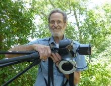 Ron Goor ’62 holding a camera with a butterfly resting on it